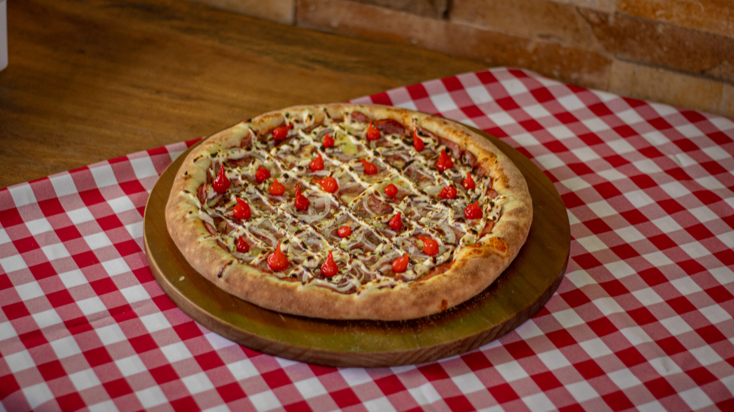 Pizza da Dom servida sobre uma mesa com toalha xadrez